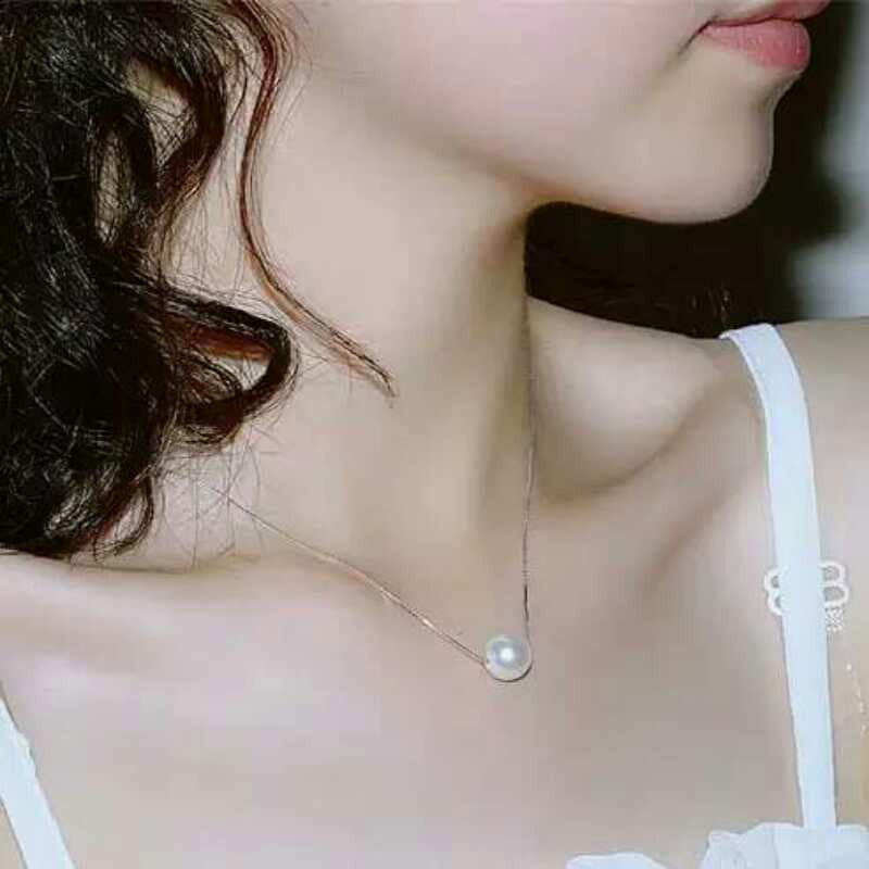 Woman wearing faux pearl clavicle necklace at collarbone

