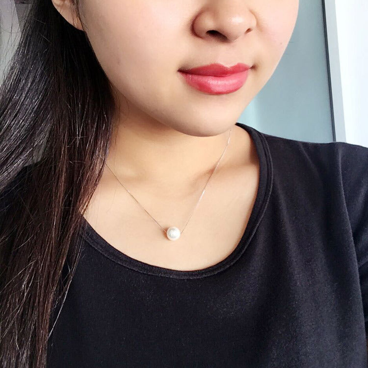 Woman wearing faux pearl clavicle necklace at collarbone
