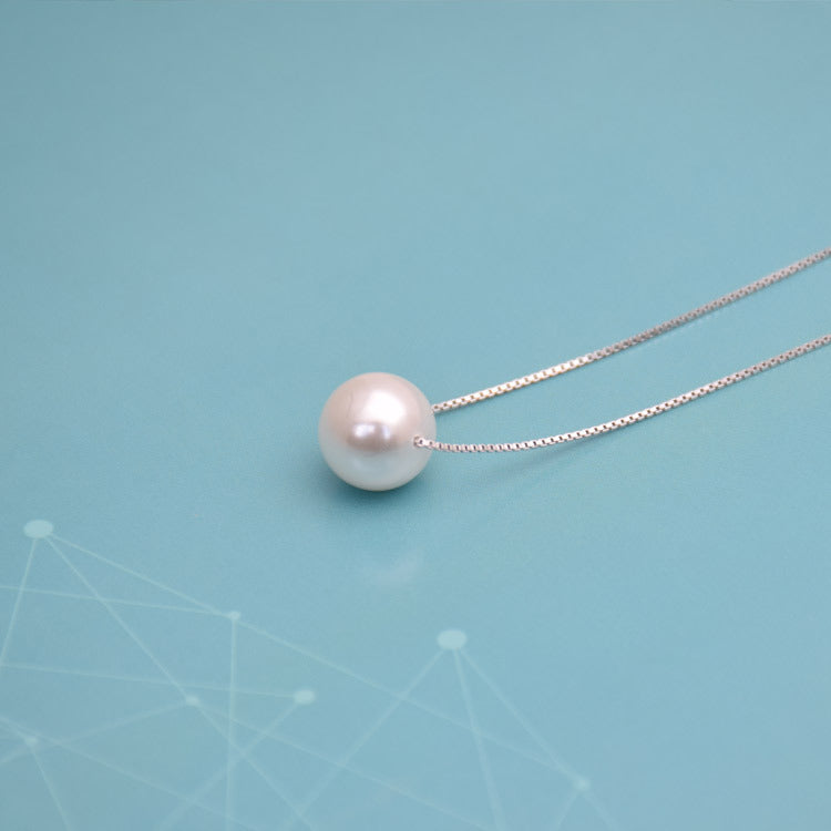 Close-up of faux pearl pendant on silver box chain necklace
