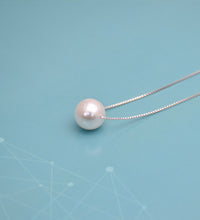 Close-up of faux pearl pendant on silver box chain necklace
